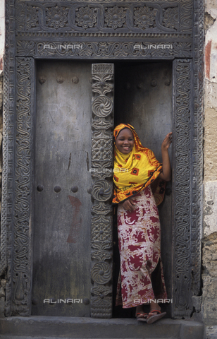 APN-F-132751-0000 - Swahili woman standing in a Zanzibar door, Bagamoyo, Tanzania - Africamediaonline/Archivi Alinari, Firenze