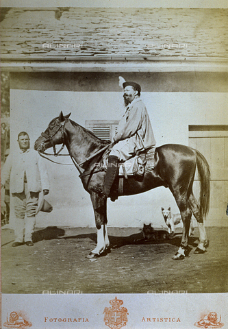 FBQ-F-001868-0000 - Portrait on horseback of Victor Emmanuel II, King of Italy, in riding clothes. In the background a man with long hair and two little dogs, in the far background a storehouse - Date of photography: 1862 - 1874 - Alinari Archives, Florence