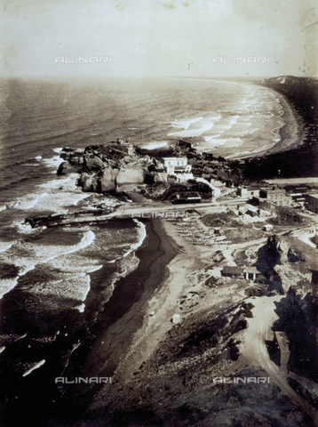 FVQ-F-045742-0000 - Veduta dall'alto di un tratto di costa con mare mosso. Al centro dell'immagine un piccolo promontorio roccioso con strutture abitative. Sulla spiaggia alcune barche tratte in secca - Data dello scatto: 1935 - Archivi Alinari, Firenze