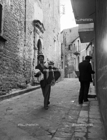 MFV-F-NS0184-0000 - Nostro Sud: un uomo con stoffe in braccio - Data dello scatto: 1953-1954 - Foto di Fosco Maraini/Proprietà Gabinetto Vieusseux © Archivi Alinari