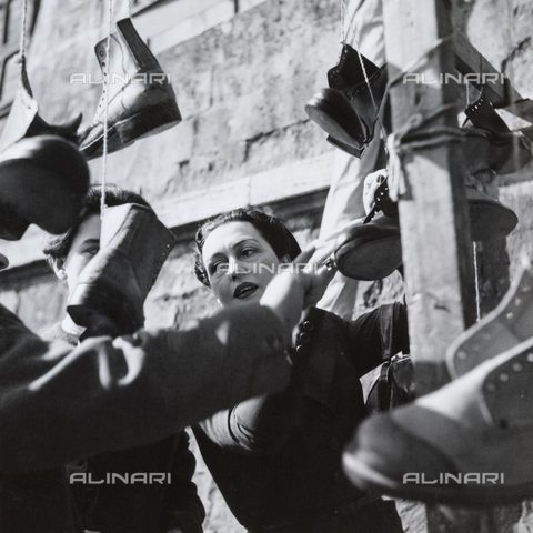 MFV-F-NS0474-0000 - Nostro Sud: signora che compra le scarpe al mercato - Data dello scatto: 1950-1956 - Foto di Fosco Maraini/Proprietà Gabinetto Vieusseux © Archivi Alinari