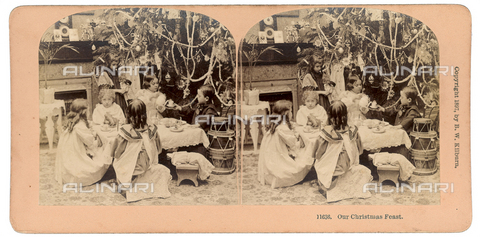 OTC-F-000118-0000 - Veduta di interno natalizio. Ritratto di gruppo di bambini seduti attorno ad un piccolo tavolo intenti a prendere tè accanto all'albero di Natale, fotografia realizzata da B.W. Kilburn, 1897, Colorado, New Hampshire, Littleton - Data dello scatto: 1897 - Archivi Alinari, Firenze
