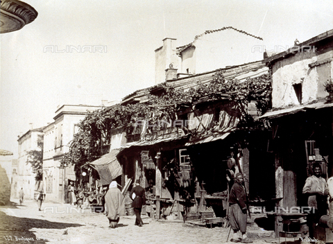 PDC-A-004568-0013 - A street in Istanbul with passersby. In the foreground a shop selling objects in iron - Date of photography: 1870-1875 ca. - Alinari Archives, Florence