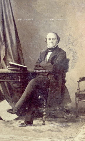 PDC-F-000611-0000 - Portrait of a man sitting at a table on which some books can be seen. The man has his arms folded and is wearing a redingote - Date of photography: 1854-1864 ca. - Alinari Archives, Florence