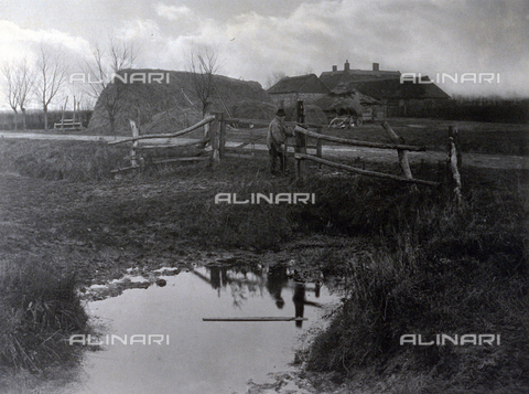 PDC-F-000684-0000 - Country landscape with houses and farm buildings. In the foreground a marsh bordered by a fence at which a farmer is protrayed - Date of photography: 1886 ca. - Alinari Archives, Florence