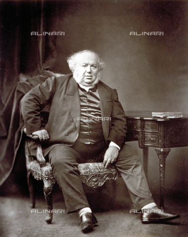 PDC-S-000312-0001 - Portrait of Jules Janin sitting in armchair, besides a writing desk, dressed in jacket and satin vest. His face, with receding hairline, is framed by long white sideburns - Date of photography: 1860-1865 - Alinari Archives, Florence