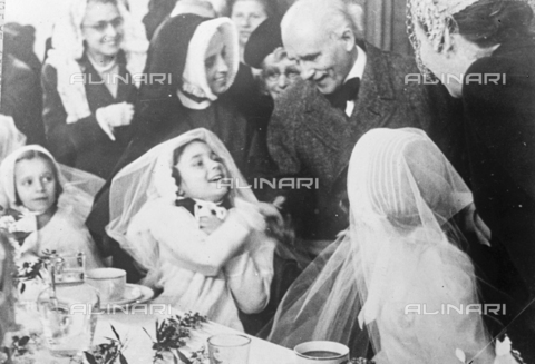 TOP-S-000147-5784 - Conductor Arturo Toscanini greets Giacomo Puccini's granddaughter Roberta Bouyeure on the day of her first communion - Date of photography: 08/05/1946 - TopFoto / Alinari Archives