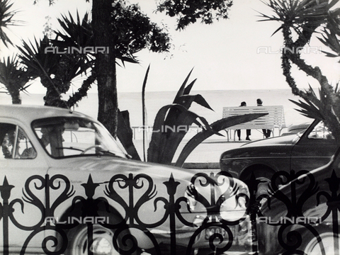 VZA-F-000465-0000 - Benches on the promenade.  View though a gate of the waterfront with cars and two men sitting on a bench - Date of photography: 1950-1960 ca. - Alinari Archives, Florence