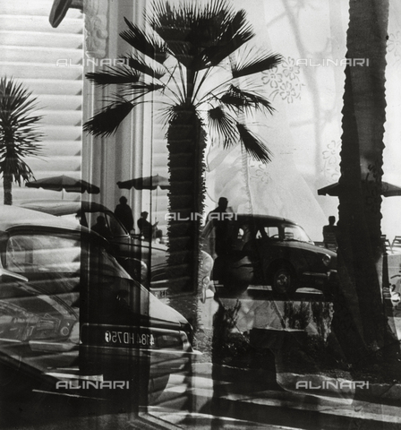 VZA-F-000470-0000 - "Finestra sulla Promenade des Anglais" (Window on the Promenade des Anglais).  View of the Nice seafront with cars, palm trees and people walking or sitting under beach umbrellas - Date of photography: 1950-1960 ca. - Alinari Archives, Florence